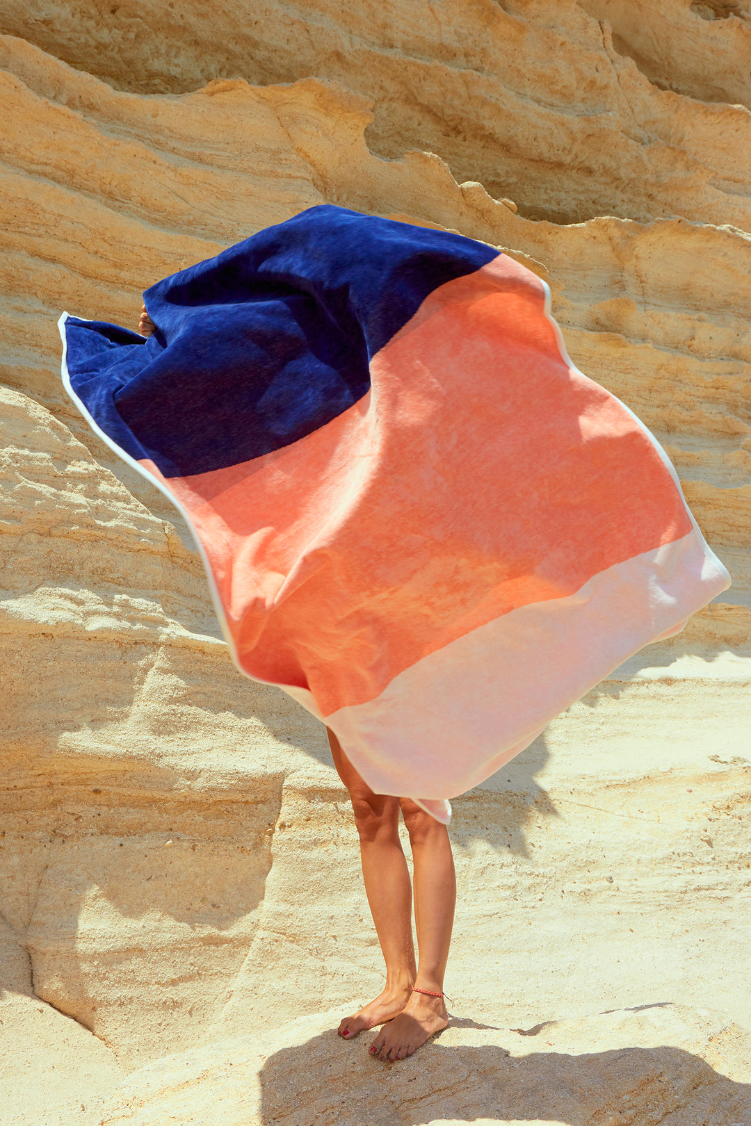 "Konoh" beach towel launch into the air. Dark blue, creamy pink and white colors in big blocks composing a beautiful design. Large beach towel that doesn't get blown by the wind. Super soft texture as it i made with organic cotton.