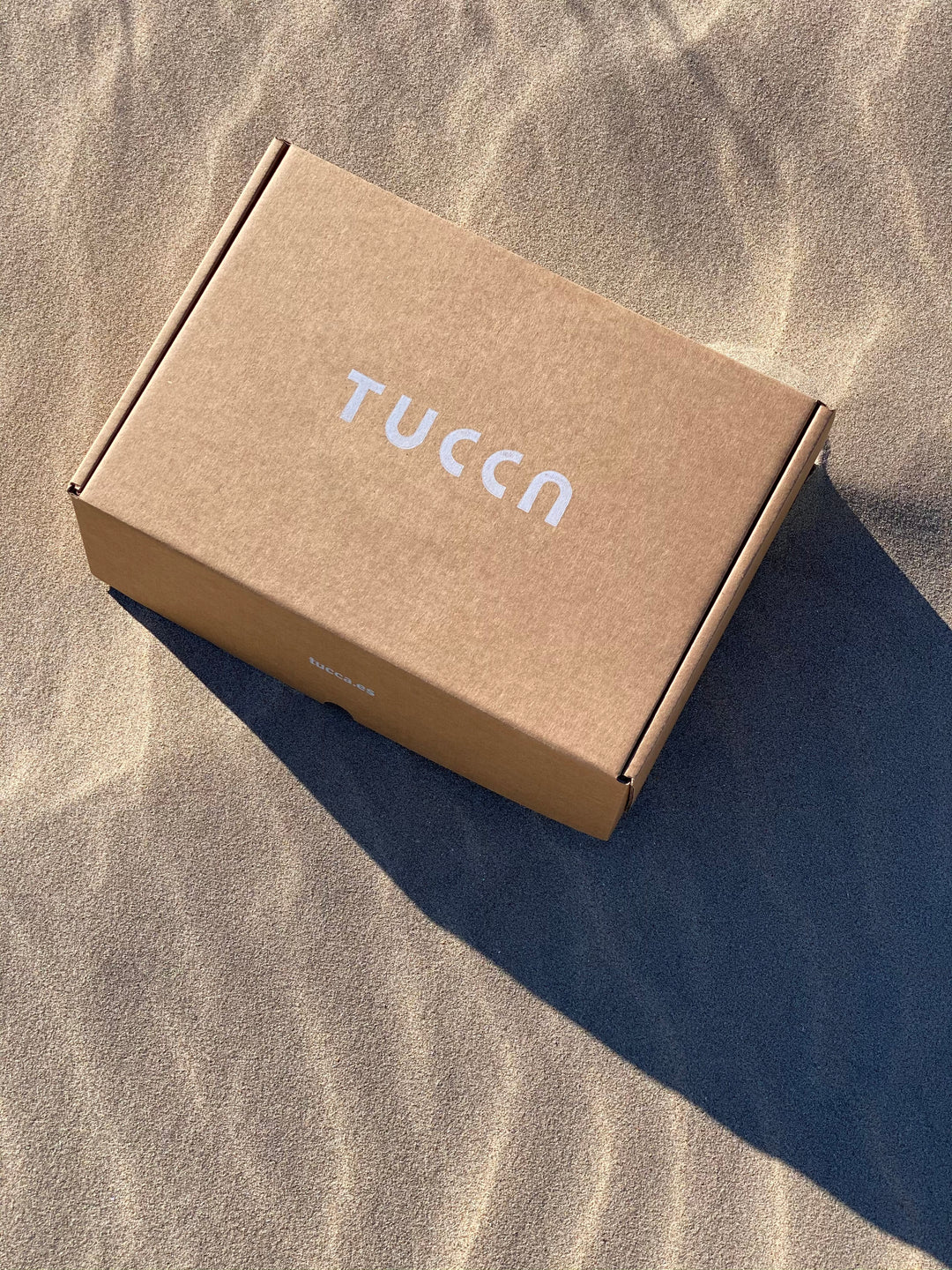 Beach towel packaging on the sand of the beach. No plastic packaging and natural materials