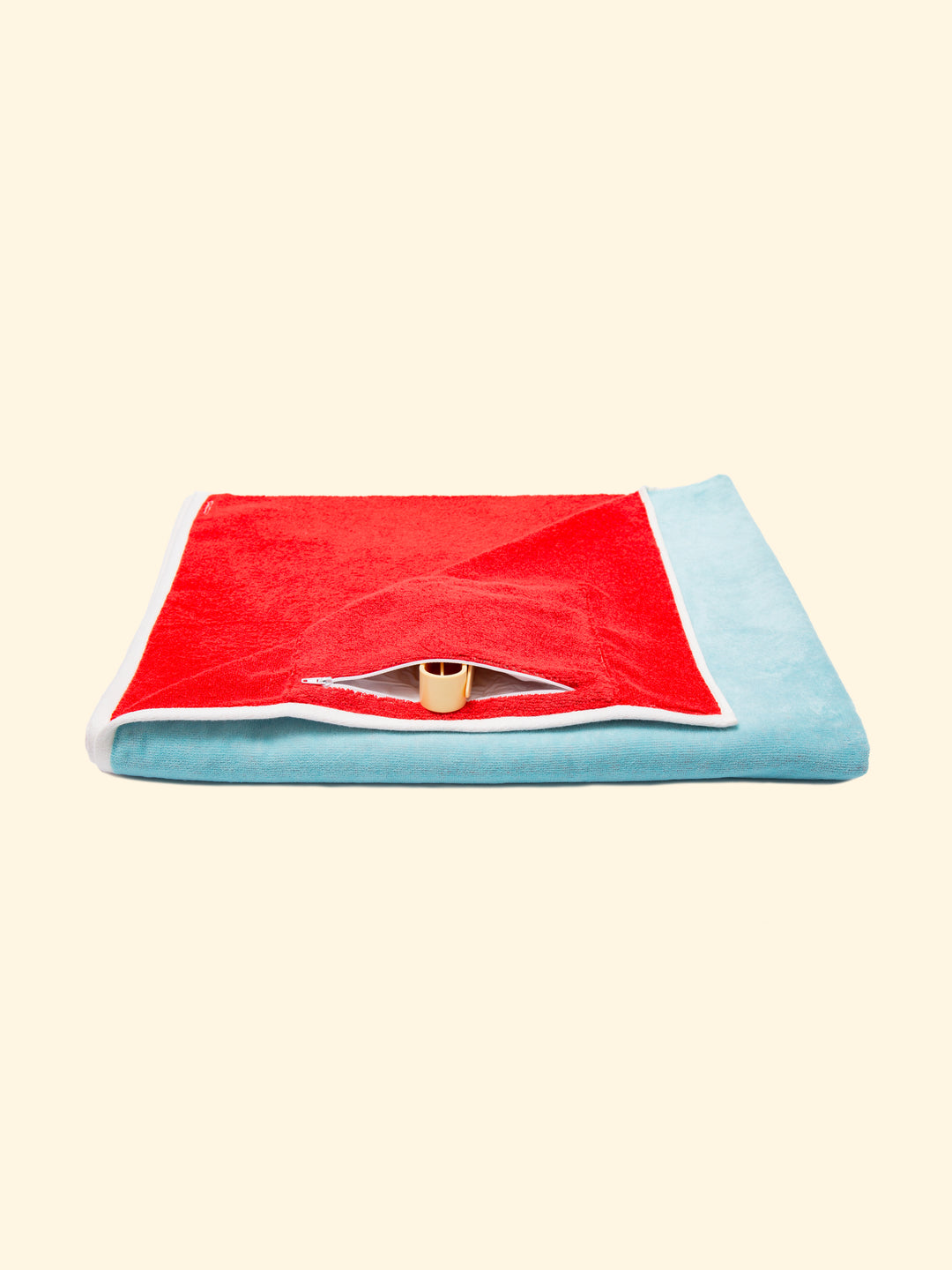 Model Berry of Tucca beach towel folded while showing its zipper closure waterproof hidden pocket, that can be used to store your phone or other belongings as well as to keep your Tucca pins as the pictures shows. The ones that can be used to fix your beach towel to the sand.