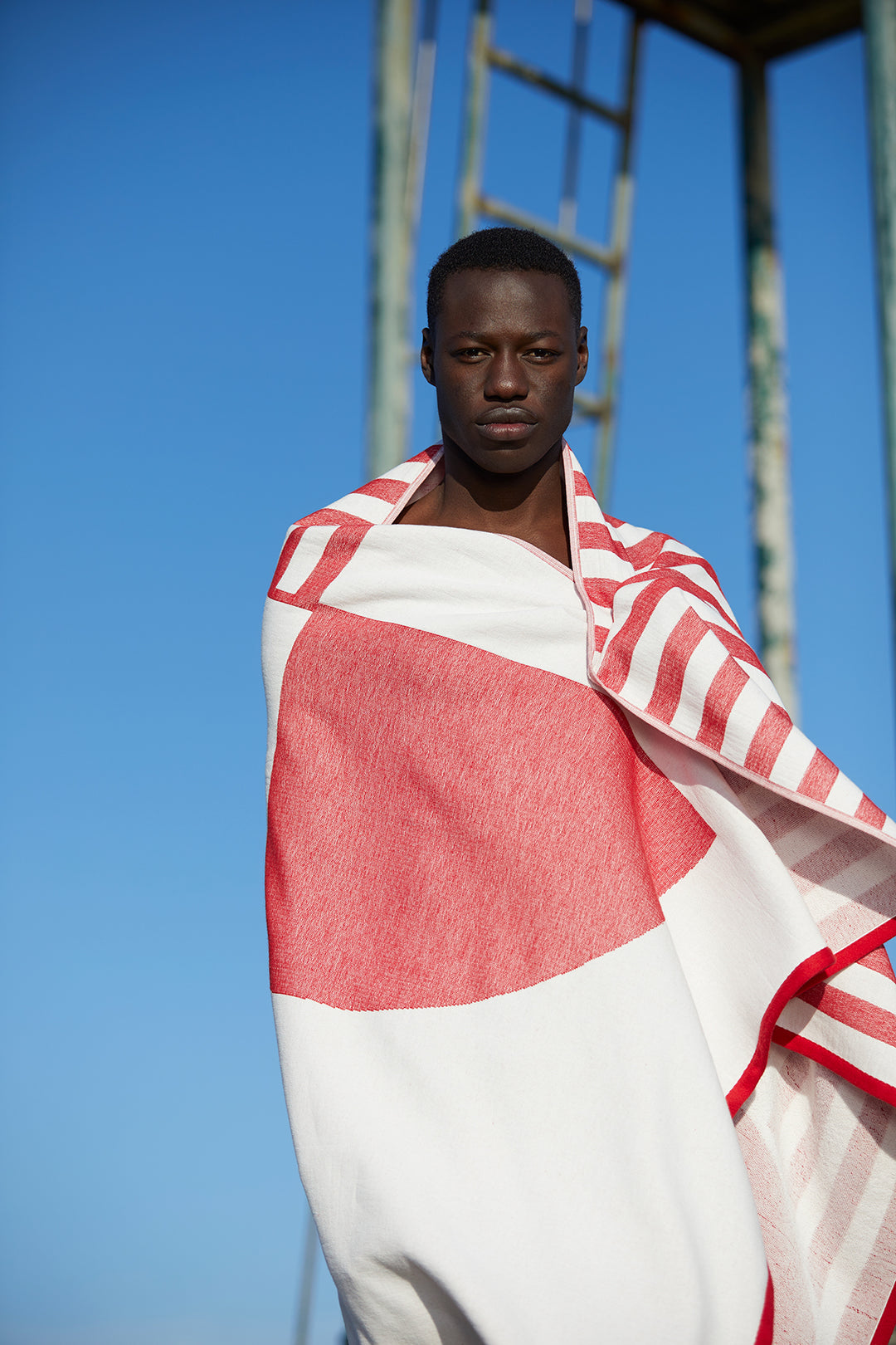 Model drying himself with the Tucca "Crassa" style. An extra light beach towel that doesn't get blown by the wind. Super soft texture as it is made with 100% organic cotton.