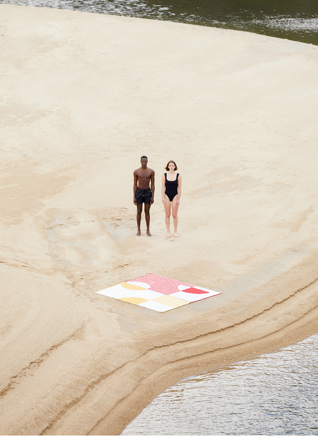 Two beach towels connected with each other. The pictures shows the connectable designs of Danai and Crassha premium ligh beach towels. A couple enjowying the beach togehter with their beach towels connected together.