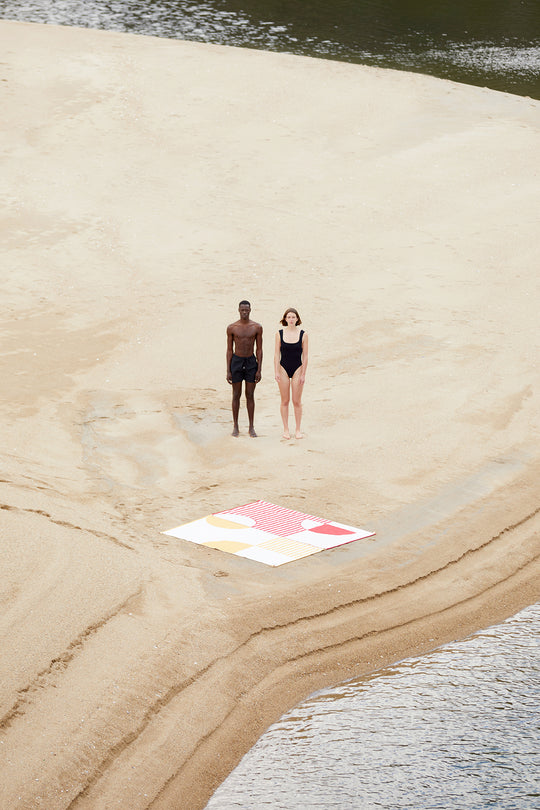 Two beach towels connected with each other. The pictures shows the connectable designs of Danai and Crassha premium ligh beach towels. A couple enjowying the beach togehter with their beach towels connected together.