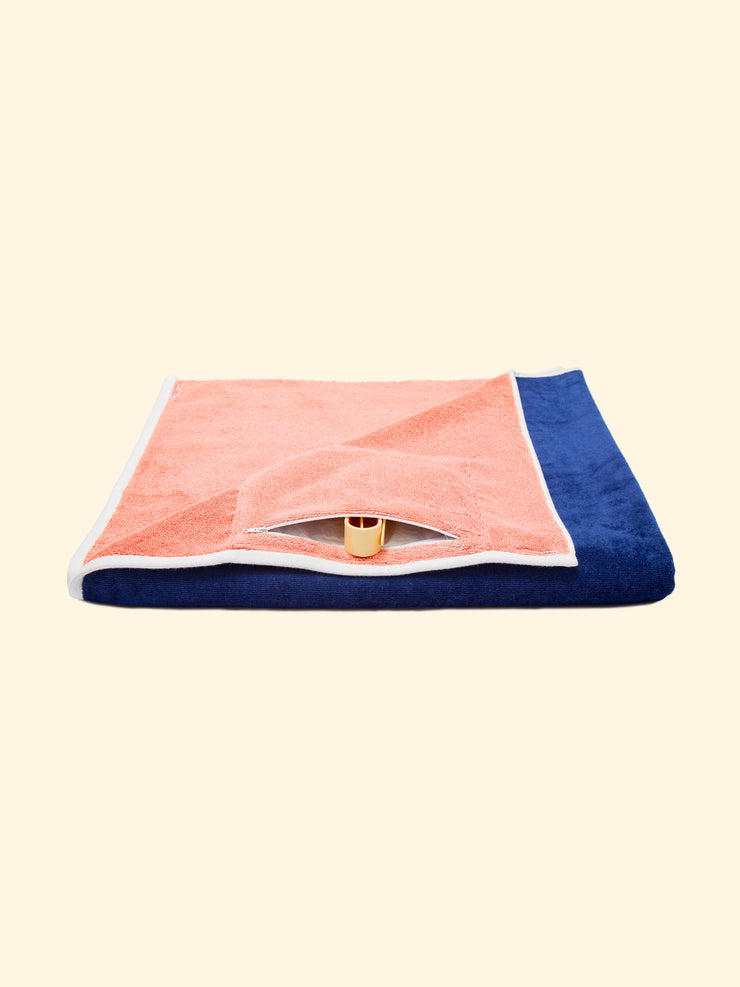 Model “Konoh” of Tucca beach towel folded while showing its zipper closure waterproof hidden pocket, that can be used to store your phone or other belongings as well as to keep your Tucca pins as the pictures shows. The ones that can be used to fix your beach towel to the sand.